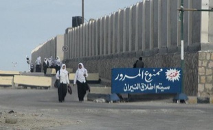 De jeunes Egyptiennes passent devant une pancarte stipulant "Interdiction de passer sous peine de tirs" à Al-Arish dans le Sinaï, le 17 novembre 2014