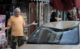 Un habitant de Tel Aviv devant un véhicule touché le 10 juillet 2014 par une roquette palestinienne