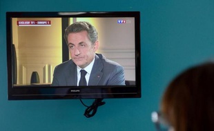 Une femme regarde Nicolas Sarkozy lors de son intervention télévisée pré-enregistrée, le 2 juillet 2014 à Paris