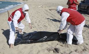 Des membres du Croissant Rouge Libyen près du corps d'un migrant ayant péri dans un naufrage, le 26 juillet 2019 près de Khoms, en Libye