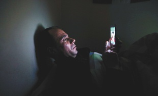 Un homme utilise son smartphone en pleine nuit (photo d'illustration)