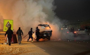 Des pompiers égyptiens autour d'un véhicule incendié lors de heurts entre la police et des supporteurs de foot au Caire le 8 février 2015
