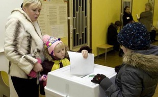 Un enfant glisse un bulletin dans l'urne sous l'oeil de sa mère à Moscou, le 2 décembre 2007.