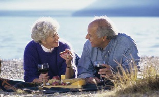 Un couple de seniors pique-nique sur la plage.
