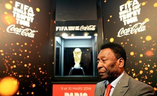 Brazilian football legend Pele answers journalist's questions next to the FIFA World Cup trophy during a press conference, on March 9, 2014 outside the Hotel de Ville in Paris. The FIFA World Cup trophy arrived with its ambassador Pele in Paris on March 9, 2014 and will be exhibited on the Hotel de Ville plaza until March 10. AFP PHOTO / FRANCK FIFE