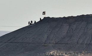 Des jihadistes à côté d'un drapeau du groupe Etat Islamique au sommet d'une colline surplombant la ville de Kobané, le 6 octobre 2014 en Syrie