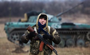 Un militant prorusse tient une kalachnikov devant un tank pris aux forces ukrainiennes à Ilovaisk le 18 novembre 2014
