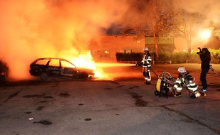 Des pompiers tentent d'éteindre des voitures incendiées à Kusta, une banlieue de Stockholm lors des émeutes en Suède le 21 mai 2013.