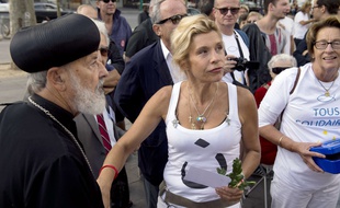 French anti-gay marriage activist Virginie Tellene, also known as Frigide Barjot (C) and Bishop Abba Athanasios from the French Copte Orthodoxe church take part in a protest in support to the Christian populations in Iraq, on September 14, 2014 in Paris. Threats by jihadists have sent a fresh wave of Christians fleeing their Iraqi homeland, bustling from exodus to exodus in search of a safe haven to rebuild their lives. AFP PHOTO / ALAIN JOCARD