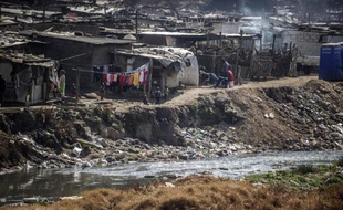 Des enfants d'un bidonville jouent aux abords d'une rivière polluée le 15 juillet 2014 à Johannesburg