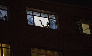 Un homme à sa fenêtre, la nuit, à Madrid.