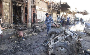 Un membre des forces de sécurité irakiennes inspecte le site d'un attentat à Hilla, en Irak, le 20 mars 2012.