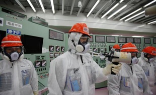 Photo du personnel de la firme japonaise Tepco en train de mesurer par dosimètre les radiations dans la salle de contrôle des réacteurs 1 et 2 de la centrale de Fukushima, le 10 mars 2014