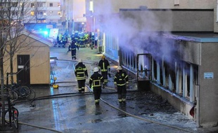 Des pompiers sur le site d'un incendie causé par un engin jeté de l'extérieur dans une mosquée du centre de la Suède, le 25 décembre 2014 à Eskilstuna