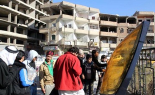 Une image du 24 décembre 2014 montrant des Syriens observant les débris d'un avion jordanien qui s'est écrasé dans la région de Raqa