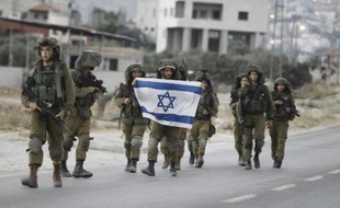 Des soldats israéliens brandissent le drapeau de l'Etat hébreu en patrouillant dans les rues de Beit Furik, en Cisjordanie, le 20 juin 2014