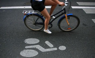 Une femme sur un vélo dans une voie réservée aux cycles.