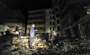 Des carabiniers italiens inspectent les décombres lors d'une patrouille nocturne, après le séisme dévastateur du 6 avril 2009 à L'Aquila.