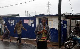 Des passants devant l'école qui sert de centre d'isolement des malades d'Ebola, le 17 août 2014 dans un quartier de l'ouest de la capitale Monrovia, au Liberia