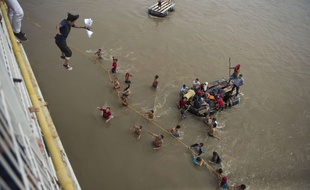 Des migrants honduriens sautent d'un pont bloqué à la frontière avec le Mexique pour continuer leur chemin vers le nord, le 19 octobre 2018.