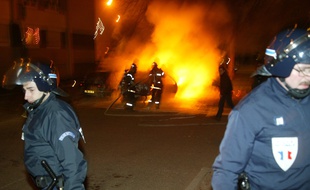 Des CRS délimitent un périmètre de sécurité autour de véhicules incendiés dans la nuit de la Saint-Sylvestre dans le quartier de l'Elsau à Strasbourg (archives).