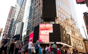 Les touristes s'arrêtent devant le panneau d'affichage endommagé par un incendie à Times Square, le 18 mai 2019.