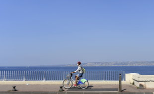 Un cycliste avec un masque sur la Corniche