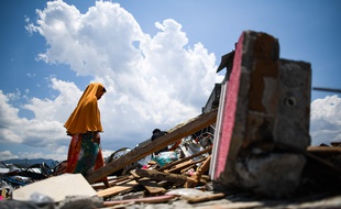 Une femme cherche des objets à récupérer dans les décombres après le séisme suivi d'un tsunami en Indonésie.