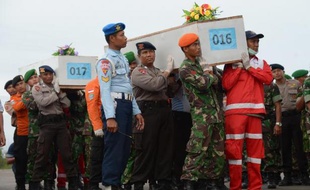 Des officiers indonésiens portent le 2 janvier 2015 les corps de passagers du vol AirAsia repêchés en mer et qui vont être acheminés vers la ville indonésienne de Surabaya