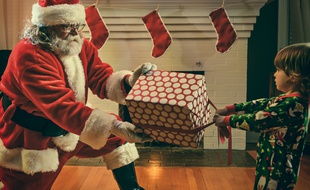 Un père Noël qui hésite à donner un cadeau à un enfant.