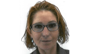 Elle est vêtue d'une jupe et d'une veste de survêtement noirs.