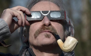 Un homme regarde l'éclipse solaire partielle à travers des lunettes de protection, le 20 mars 2015, à Strasbourg