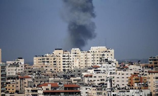 De la fumée s'élève au dessus d'un immeuble touché par une frappe aérienne israélienne à Gaza le 17 juillet 2014