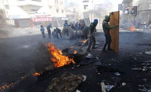 Des Palestiniens se protègent derrière une porte lors d'affrontements avec l'armée israélienne à Hébron le 3 avril 2013.