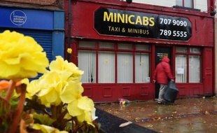 Des fleurs déposées devant l'agence de taxis où avait travaillé l'humanitaire britannique assassiné, Alan Henning, à Eccles au nord-ouest de l'Angleterre, le 4 octobre 2014