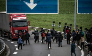 Des migrants tentent de bloquer un camion sur une route d'acès au tunnel sous la Manche le 3 décembre 2015 à Coquelles