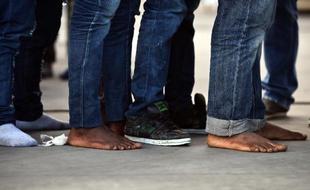 Des migrants sauvés en mer font la queue pour recevoir des vêtements et de la nourriture, le 20 octobre 2014 dans le port de Palerme, en Italie