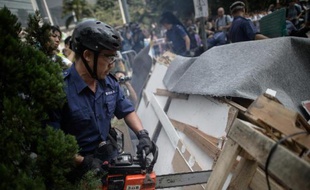 Des policiers démantèlent à la tronçonneuse des barricades le 14 octobre 2014 à Hong Kong