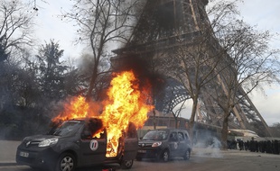 Une voiture de Sentinelle brûle devant la Tour Eiffel, en marge d'une manifestation de "Gilets jaunes" à Paris le 9 février 2019.