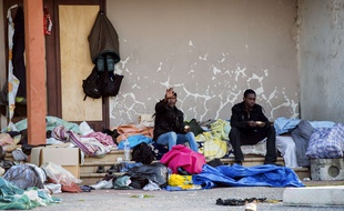 Migrants sit on the stairs of a building in Calais, northern France, on August 5, 2014. Dozens were hurt on August 5 after clashes broke out in the northern French port of Calais between hundreds of African migrants seeking to cross the Channel to England. Police reinforcements were called to break up fights between groups of mainly Eritrean and Sudanese migrants that left 51 people hurt, one of whom was sent by helicopter to hospital with serious head injuries. AFP PHOTO / PHILIPPE HUGUEN