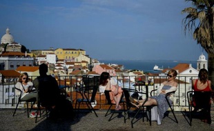 Des touristes profitent du soleil sur une terrasse, dans le quartier d'Alfama, le 15 avril 2014 à Lisbonne