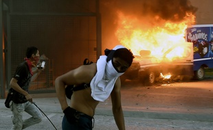 Des étudiants près d'une voiture en feu lors d'une manifestation devant le siège du gouvernement régional de l'Etat du Guerrero, dans le sud du Mexique, le 8 novembre 2014.