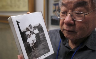 Un descendant d'une famille de Nippo-Américain pose avec une photo de sa famille internée pendant la guerre.