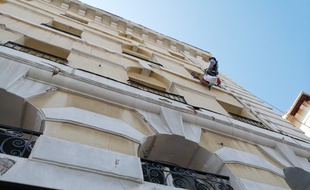 Un ouvrier répare des balcons sur la façade d'un immeuble de Marseille.