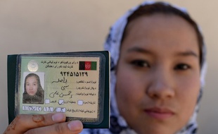 Une femme montre sa carte d'électrice à Kaboul en 2014.