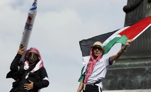 Des manifestants l'un portant une replique d'une roquette et l'autre brandissant un drapeau palestinien, participent à un rassemblement contre les raids israéliens sur Gaza, à Paris le 13 juillet 2014