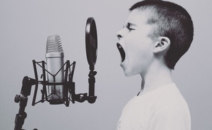 Illustration d'un enfant chantant devant un micro.