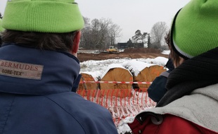 Avec leurs bonnets verts sur la tête, deux opposants au projet autoroutier controversé du Grand contournement ouest de Strasbourg assistent à des travaux de terrassement à Vendenheim, à l'emplacement du futur échangeur nord.