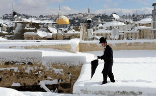 Un juif ultra-orthodoxe marche sur les toits de la vieille ville de Jérusalem, le 13 décembre 2013. Une grosse tempête de neige qui a frappé le proche-orient a paralysé la ville.