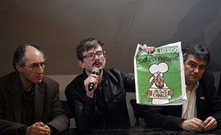 Luz, entouré de Gérard Biard et Patrick Pelloux, montre la Une de
